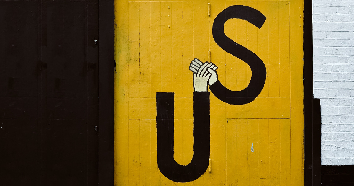 black and yellow background with letters U and S holding hands on the foreground.
